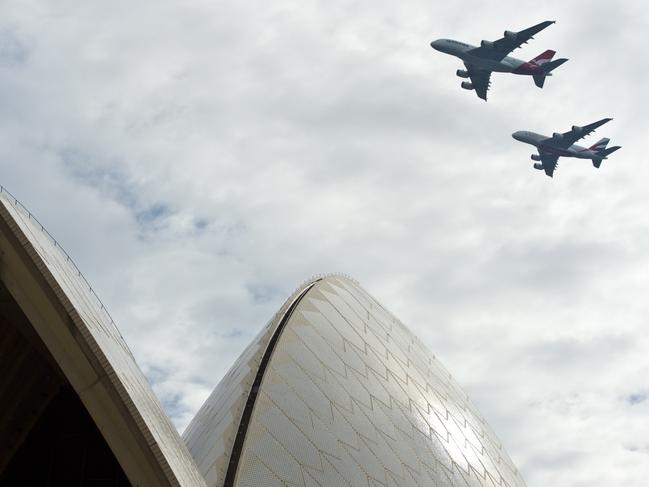 A Qantas A380, top, and an Emirates A380 fly in formation over Sydney Harbour in March 2013 when the airlines announced a partnership deal. Picture: James Morgan/Qantas