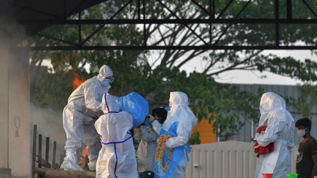 Family members wearing protective gear carry the body of a victim who died of coronavirus towards a pyre in India.