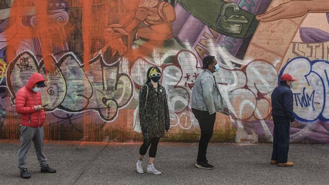 People wearing protective masks wait in line at a grocery store in Brooklyn, New York. Picture: Getty Images