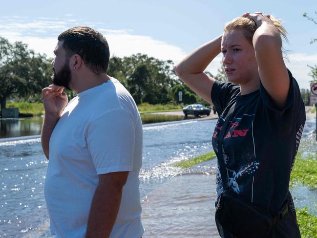 NEW PORT RICHEY, FLORIDA - OCTOBER 11: People walk through a flooded street from the rising Anclote River as Florida tries to recover from Hurricane Milton on October 11, 2024 in New Port Richey, Florida. The storm made landfall as a Category 3 hurricane, causing extensive flooding and damage throughout Florida's Gulf Coast.   Spencer Platt/Getty Images/AFP (Photo by SPENCER PLATT / GETTY IMAGES NORTH AMERICA / Getty Images via AFP)