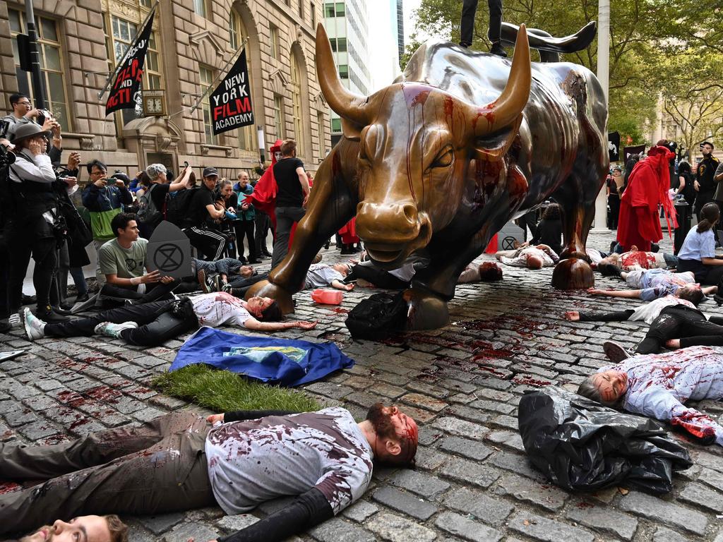 Protesters covered in fake blood gather around the Wall Street bull during an Extinction Rebellion demonstration in New York. Picture: Timothy A Clary/AFP