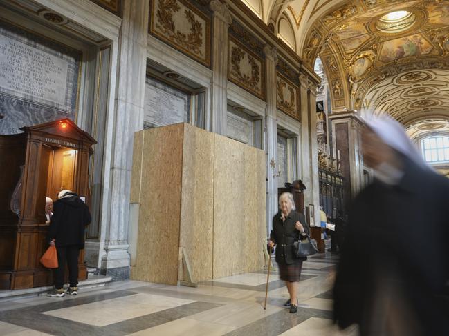 People walk past a wooden board where work in progress is taking place on the spot where Pope Francis will be buried, inside St. Mary Major basilica, in Rome, Tuesday, April 22, 2025. (AP Photo/Alessandra Tarantino)