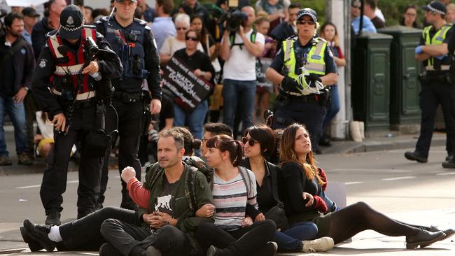 Police remove animal rights protesters from the middle of the intersection of Swanston and Flinders Street's, in front of Flinders Street Station. Picture: Stuart McEvoy