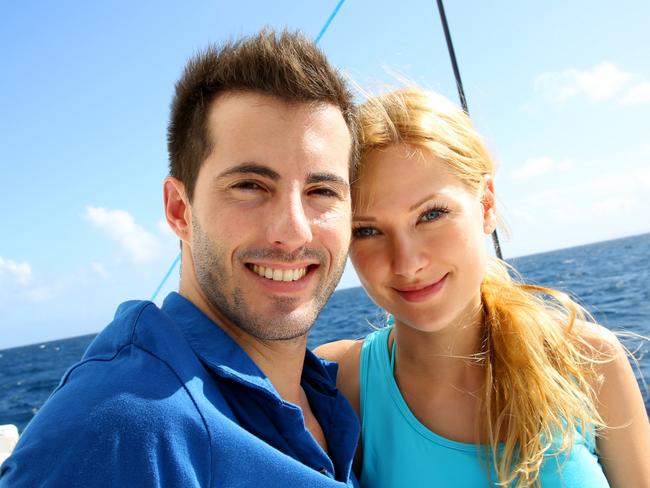 Portrait of couple sitting on the top of sailing boat. Boating generic.