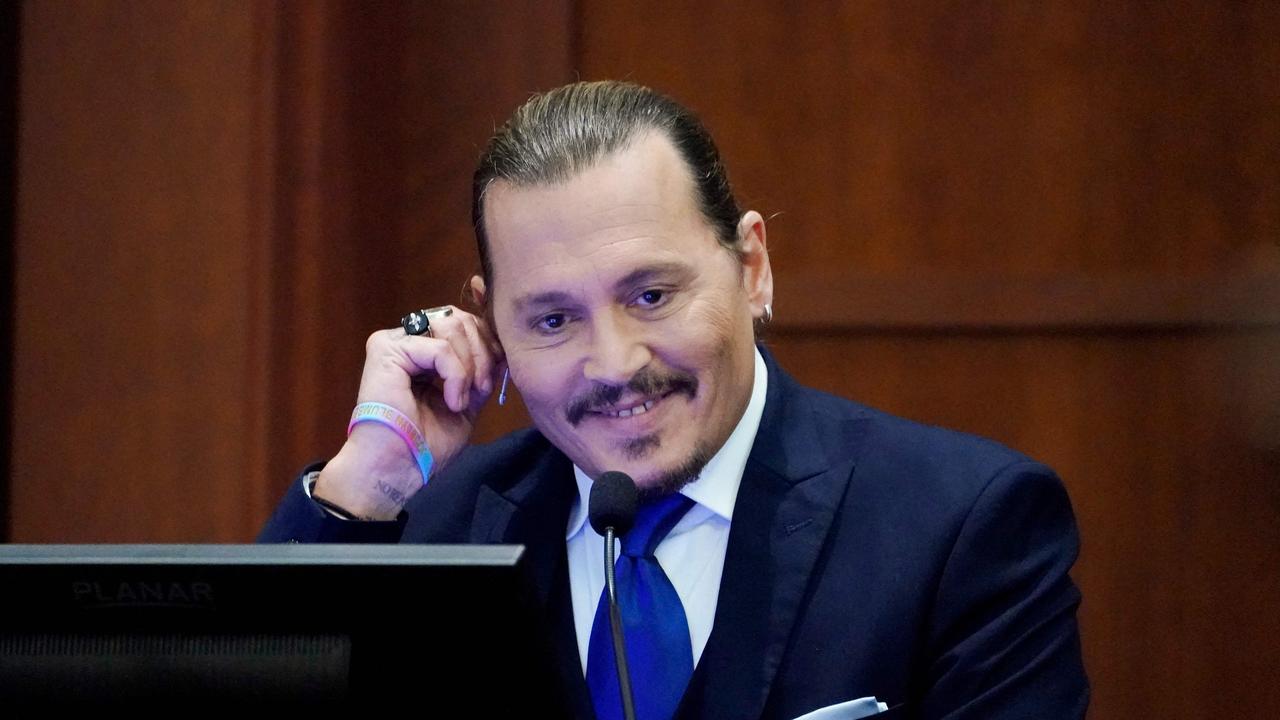 Johnny Depp laughs while on the stand. (Photo by Steve Helber / POOL / AFP)