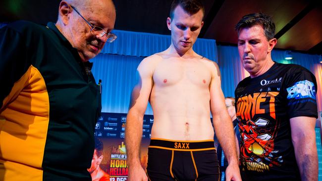 Australian boxer Jeff Horn (C) looks on during the pre-fight weigh-in at the Brisbane Convention Centre in Brisbane on December 12, 2017, the eve of the World Boxing Organisation welterweight title bout against Gary Corcoran. English challenger Gary Corcoran has claimed Australian World Boxing Organisation welterweight champion Jeff Horn is a "dirty" fighter ahead of their title bout in Brisbane on December 13. / AFP PHOTO / Patrick HAMILTON / -- IMAGE RESTRICTED TO EDITORIAL USE - STRICTLY NO COMMERCIAL USE --