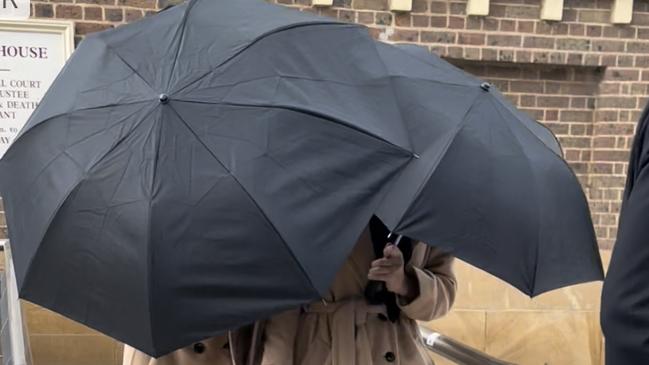 Grace and Lara Buttriss don matching outfits while hiding behind an umbrella exiting Picton Courthouse on August 19, 2022. Picture: Annie Lewis