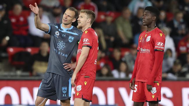 Sydney’s Alex Wilkinson, left, and Adelaide’s Ben Halloran and Al Hassan Toure discuss a pending VAR decision on the big screen. Picture: Sarah Reed