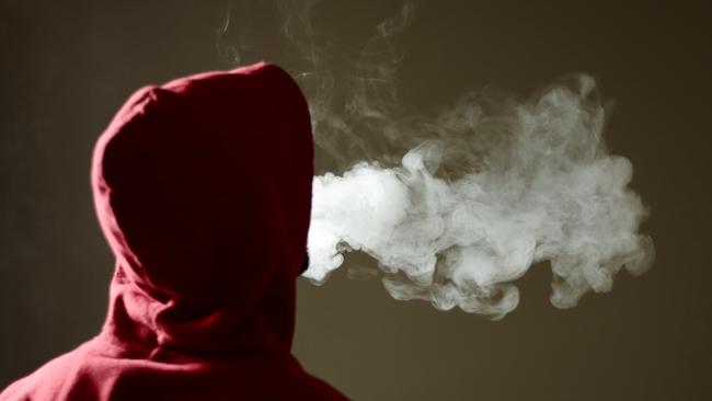 Young male in red hoodie vaping smoking, exhales thick vapour, isolated rear view Picture: iStock