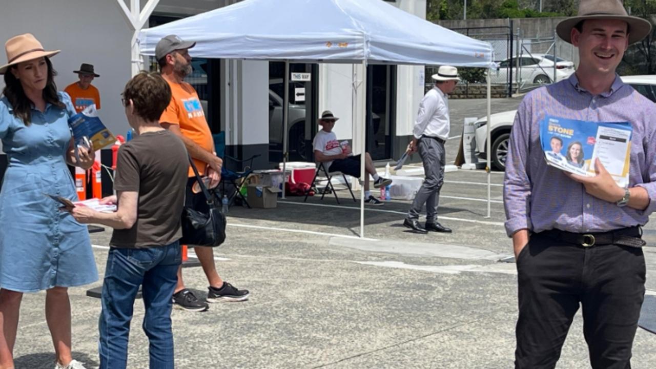 Bonney LNP MP Sam O'Connor handing out to how-to-vote cards for their candidate Bianca Stone (standing behind him) in Gaven at the pre-poll.