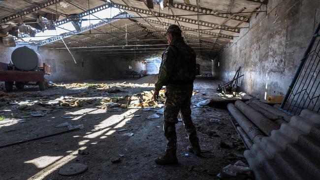 A Ukrainian army officer inspects a grain warehouse shelled by Russian forces near the frontlines of Kherson Oblast in Novovorontsovka, Ukraine. Russia has been accused of targeting food storage sites in frontline areas and generally degrading Ukraine's wheat production, potentially causing a global shortage.