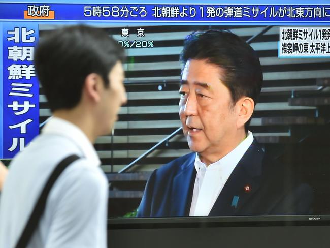 Pedestrians walk in front of a television screen displaying Japan's Prime Minister Shinzo Abe speaking to the media after the North Korean missile test. Picture: AFP photo