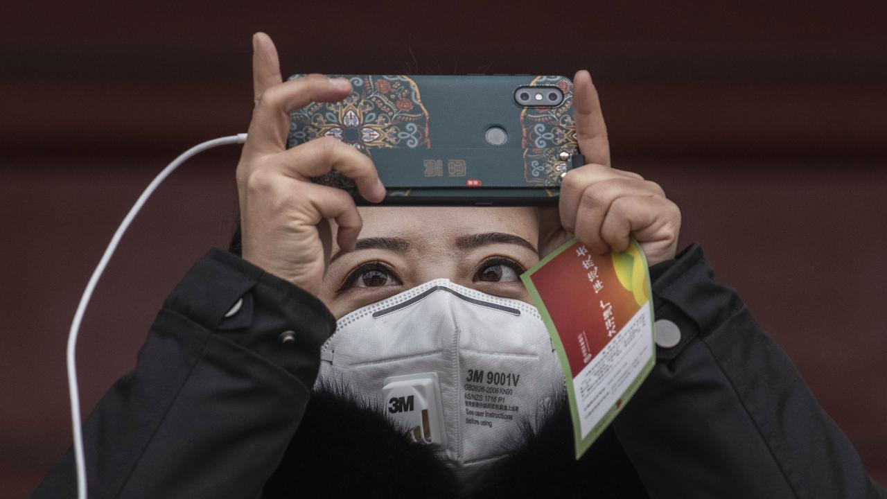 A Chinese visitor wears a protective mask as she takes a picture while touring the grounds of the Temple of Heaven, which remained open during the Chinese New Year and Spring Festival holiday on January 27, 2020 in Beijing, China. Picture: Kevin Frayer/Getty Images