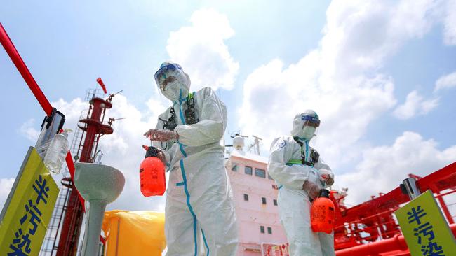 Police officers in protective gear spray Covid-19 disinfectant at Nanjing port in China’s eastern Jiangsu province. Picture: AFP