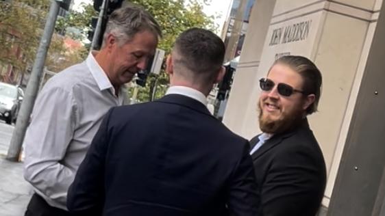 Homann (right) speaks outside court with his lawyer and support person.