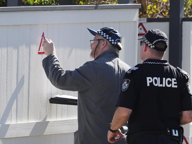 Police examine bullet holes in a fence. The scene of a police shooting at Mt Gravatt.  Pic Peter Wallis