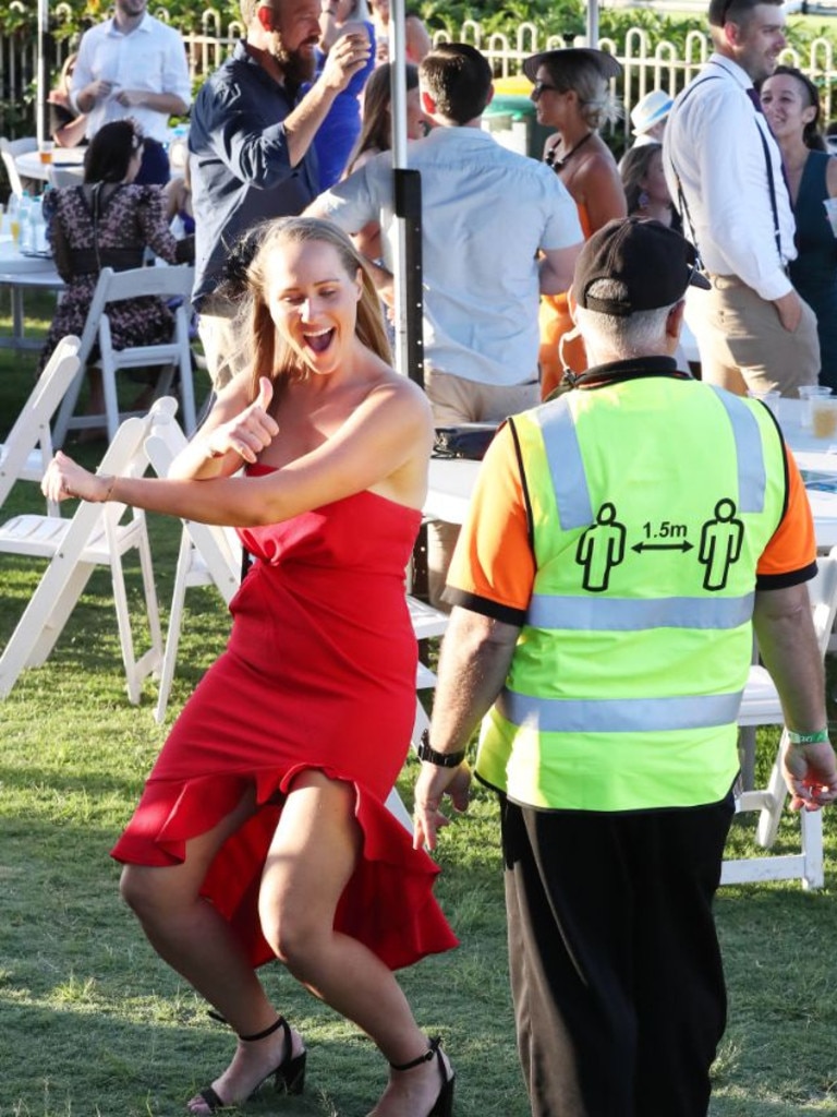 A woman dances in front of social distancing enforcement security.