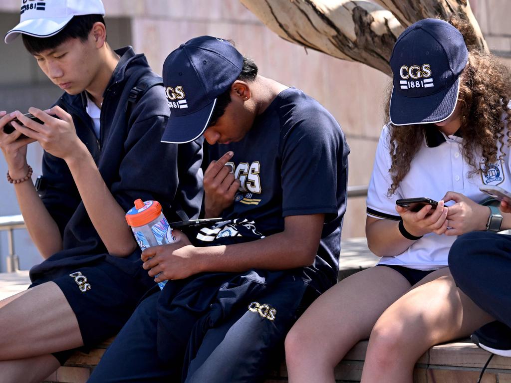 Students look at their phones in Melbourne on November 28, 2024 as Australia looks to ban children under 16 from social media with claims social media platforms have been tarnished by cyberbullying, the spread of illegal content, and election-meddling claims. Australia is among the vanguard of nations trying to clean up social media, and the age limit legislation will make it among the world's strictest measures aimed at children. (Photo by William WEST / AFP)