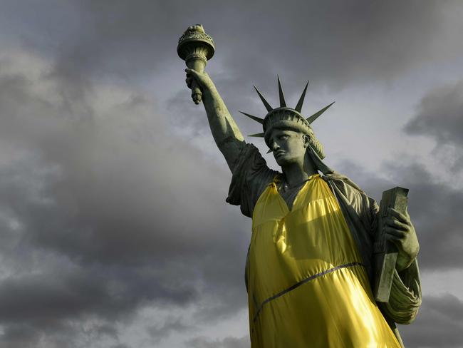 A Statue of Liberty replica wears a yellow vest, as protests in France help spur action on tax. Picture: AFP