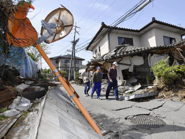 Residents walk past a house damaged by a magnitude-6.5 earthquake in Mashiki, Kumamoto prefecture, southern Japan, Friday, April 15, 2016. The powerful earthquake struck Thursday night, knocking down houses and buckling roads. (Yu Nakajima/Kyodo News via AP) JAPAN OUT, MANDATORY CREDIT