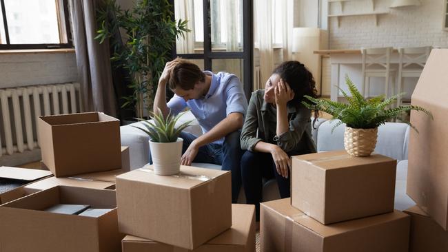 Unhappy frustrated couple sitting on couch with cardboard boxes, eviction, family having problem with dwelling, money or mortgage, worried woman and man lost home, bankruptcy or debt concept