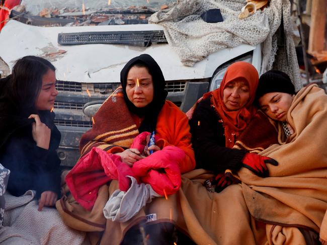 Women sit around a fire next to rubble and damages near the site of a collapsed building in the aftermath of an earthquake, in Kahramanmaras, Turkey. Picture: Reuters/Suhaib Salem