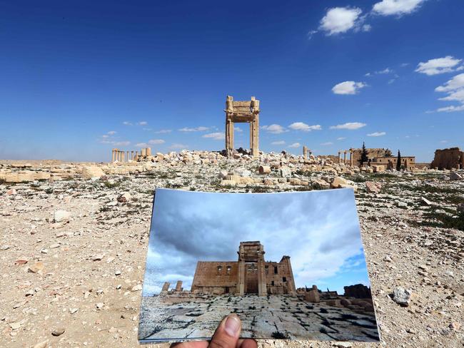 A general view taken on March 31, 2016 shows a photographer holding his picture of the Temple of Bel taken on March 14, 2014 in front of the remains of the historic temple after it was destroyed by Islamic State (IS) group jihadists in September 2015 in the ancient Syrian city of Palmyra. Picture: AFP PHOTO / JOSEPH EID