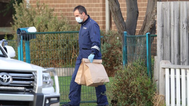 A forensic officer removes bags of evidence from the scene. Picture: David Crosling