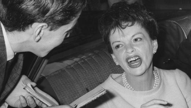 Judy Garland talks to a journalist as her car leaves Mascot airport after her arrival in Sydney in 1964.