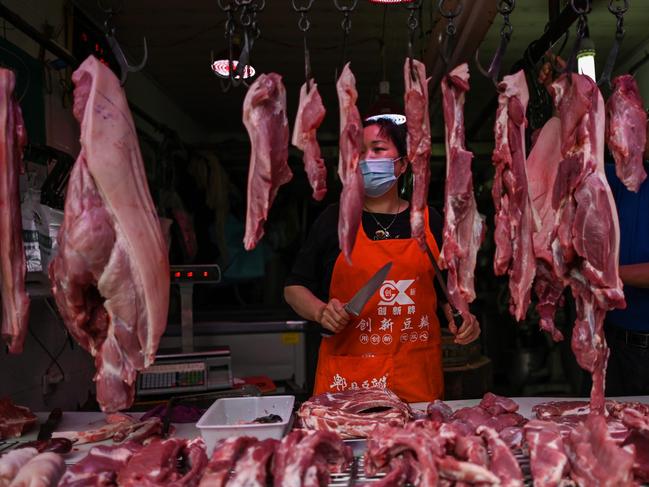 A vendor wearing a face mask works in her stall in a market in Wuhan, in China. Picture: AFP