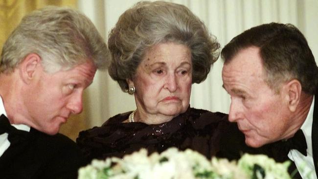 President Bill Clinton leans in to listen to former President George H.W. Bush over Lady Bird Johnson during a dinner in honour of the 200th anniversary of the White House in 2000.