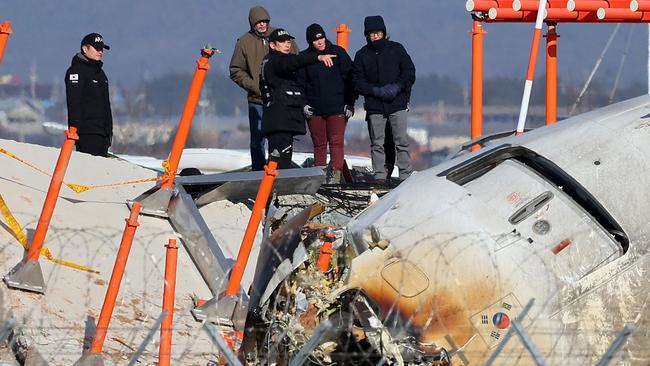 Investigators stand by the mound where the instrument landing system localiser is located, at the scene where a passenger plane crashed and burst into flames. Picture: AFP