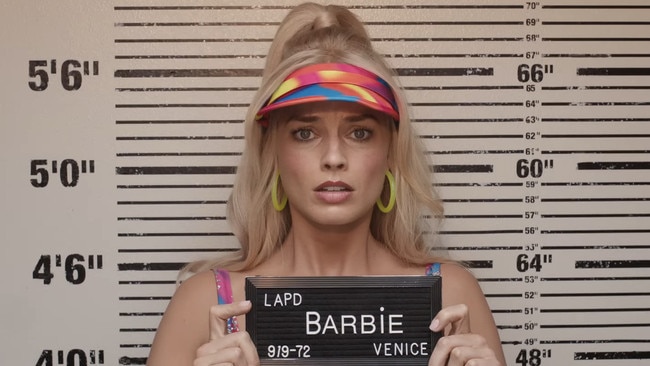 Margot Robbie as Barbie, having her mug shot taken in the 2023 film.