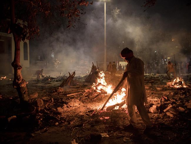 Workers at a crematorium where multiple funeral pyres are burning for patients who lost their lives to the virus in New Delhi, India. Picture: Getty Images