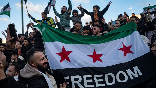 A demonstrator holds a Syrian opposition flag as members of the Syrian community chant slogans in Syntagma square in Athens to celebrate the end of the regime of Syrian dictator Bashar al-Assad. Picture: AFP