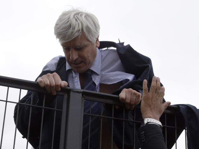 Director of Air France in Orly Pierre Plissonnier, nearly shirtless, tries to cross a fence, helped by security and police officers, after several hundred of employees invaded the offices of Air France, interrupting the meeting of the Central Committee (CCE) in Roissy-en-France, on October 5, 2015. Air France-KLM unveiled a revamped restructuring plan on October 5 that could lead to 2,900 job losses after pilots for the struggling airline refused to accept a proposal to work longer hours. AFP PHOTO / KENZO TRIBOUILLARD