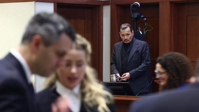 US actor Amber Heard speaks to her legal team as US actor Johnny Depp stands. Picture: AFP.