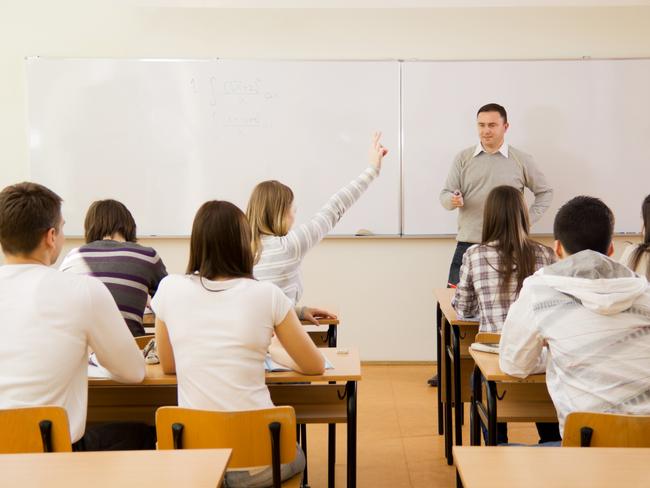 "rear view of high-school students in a classroom, during lesson. Girl responding to teacher's question."