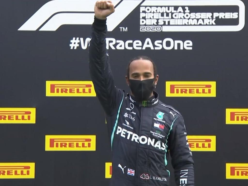 Lewis Hamilton raises his fist after accepting his winner's trophy.