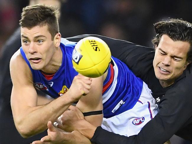 MELBOURNE, AUSTRALIA - AUGUST 19:  Josh Dunkley of the Bulldogs handballs whilst being tackled by Jack Silvagni of the Blues during the round 22 AFL match between the Carlton Blues and the Western Bulldogs at Etihad Stadium on August 19, 2018 in Melbourne, Australia.  (Photo by Quinn Rooney/Getty Images)