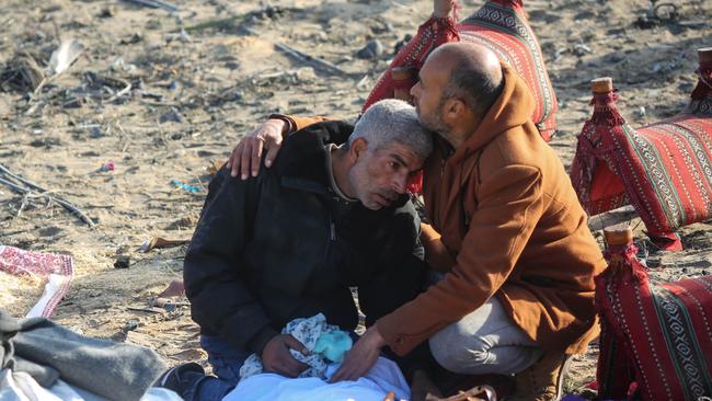 A man is comforted by another man as people inspect the damage to their homes following Israeli air strikes on Sunday in Rafah, Gaza. Picture: Ahmad Hasaballah/Getty Images