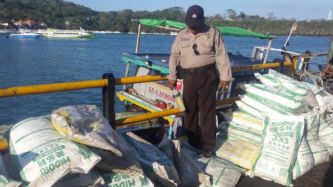 A police officer walks over bags of ammonium nitrate fertiliser discovered in waters off Bali. Picture: Supplied