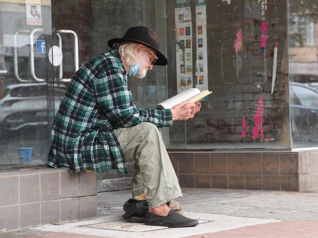 Bob Last of East Lismore reads a book outside the closed Book Warehouse on Keen St. Picture Cath Piltz