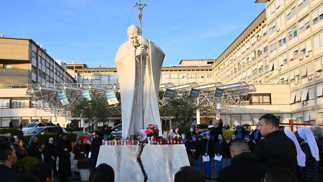 People pray at the statue of John Paul II outside the Gemelli hospital where Pope Francis is hospitalised in Rome. Picture: AFP