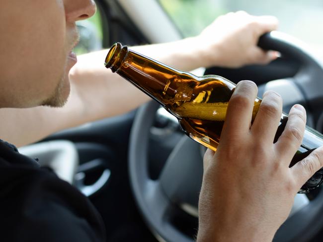 The concept of alcohol driving crime - closeup of young male driver hands with steering wheel and bottle of beer. Drink driving generic. Picture: iSTOCK