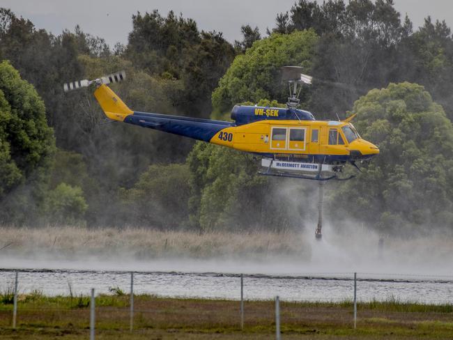 Smoke haze covers the Gold Coast Skyline from a grass fire at Carrara. A firefighting helicopter collects water from Judy Turners property in Carrara . Picture: Jerad Williams