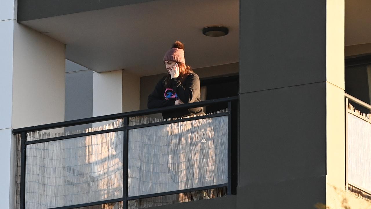 A resident at an apartment complex in Blacktown stands on her balcony as police manage the building. Picture: NCA NewsWire/Jeremy Piper