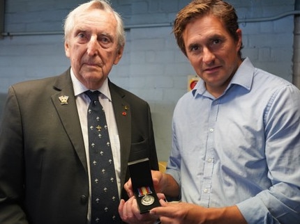 John Robinson (left) holding the Nuclear Test Medal alongside British Minister of State for Veterans' Affairs Johnny Mercer MP.