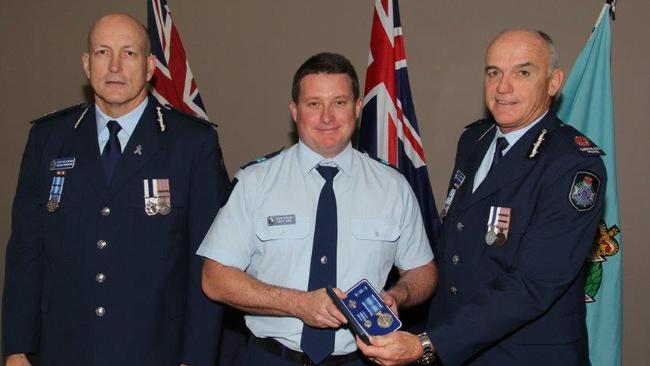 Senior Constable Brett Forte, centre, receives a service medal during his time at Caboolture Police Station.