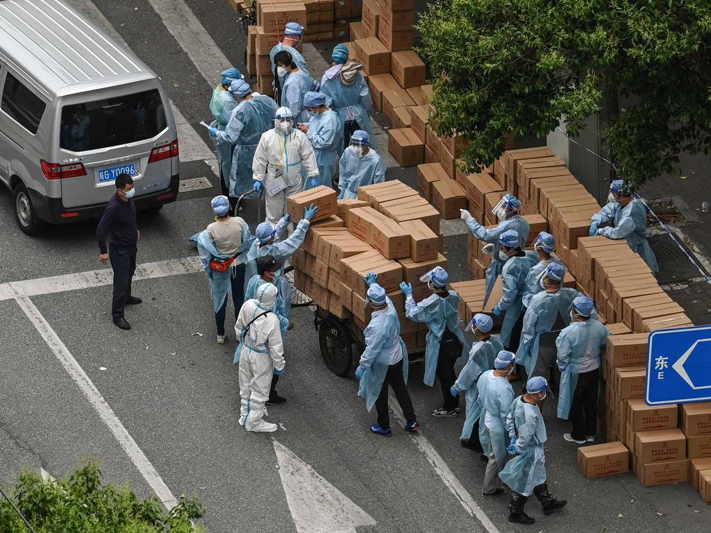 Workers wearing protective gear stack up boxes with food over a cart to deliver in a neighbourhood during a Covid-19 lockdown in Shanghai. Picture: AFP